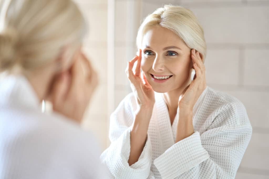 Cosmetic model woman looking at her reflection in a mirror