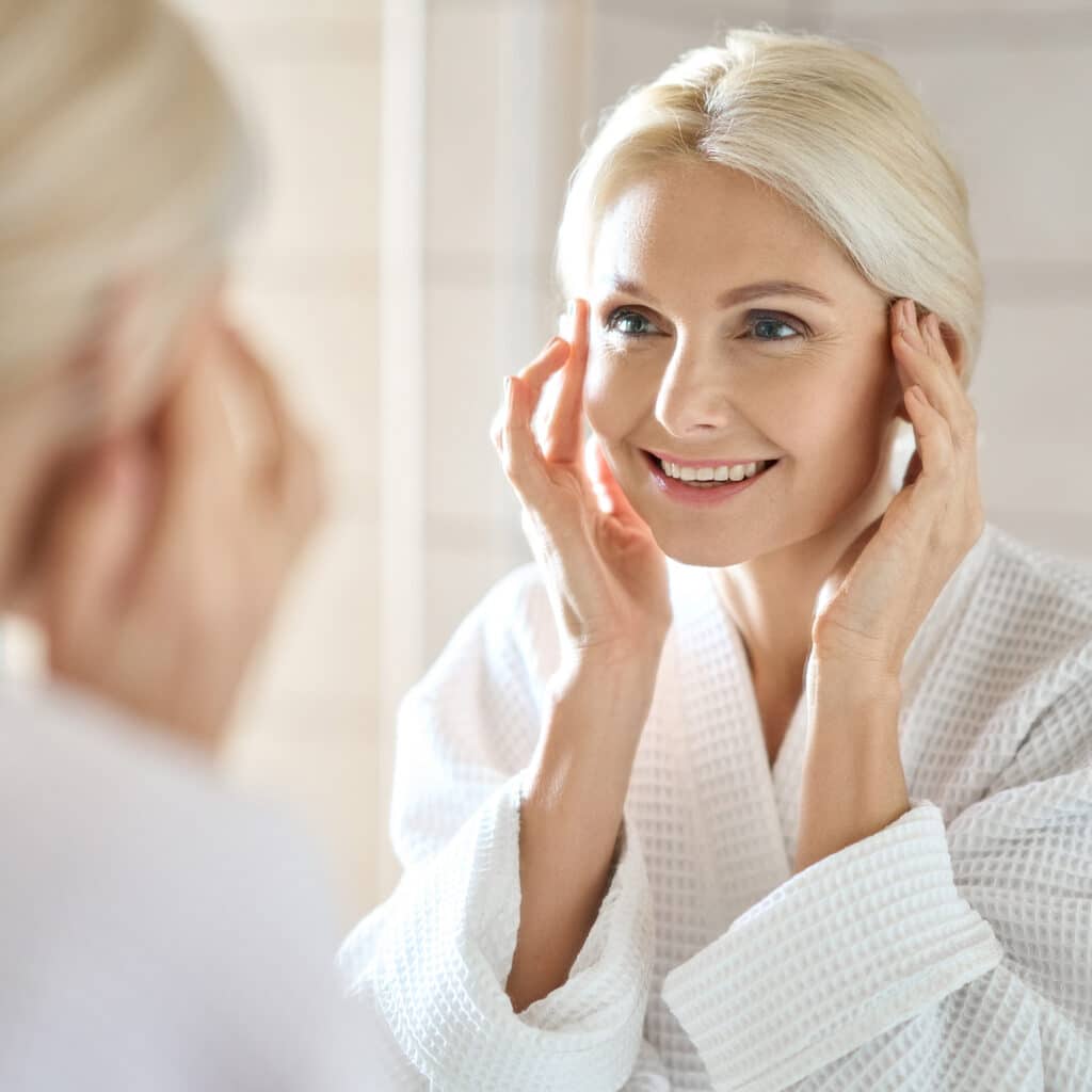 Cosmetic model woman looking at her reflection in a mirror